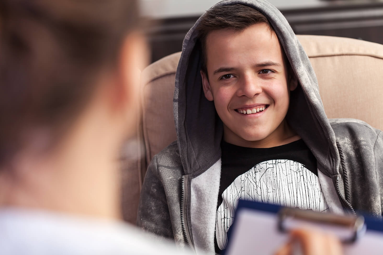 A young teen boy sits in a counseling session representing teens who face unique challenges growing up who could benefit from the support of Therapy for Teens in Arlington, MA.