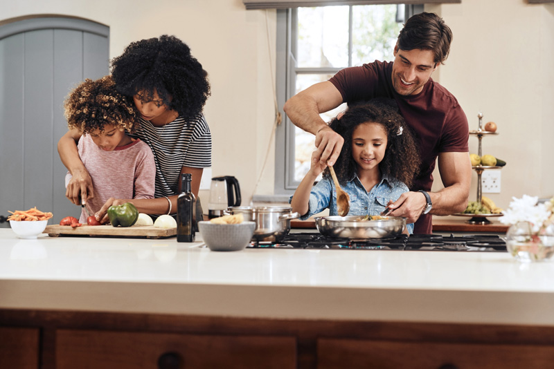 A family prepares a healthy meal in their kitchen together representing parents utilizing skills learned from parenting support in Arlington, MA like Therapy for Teens.
