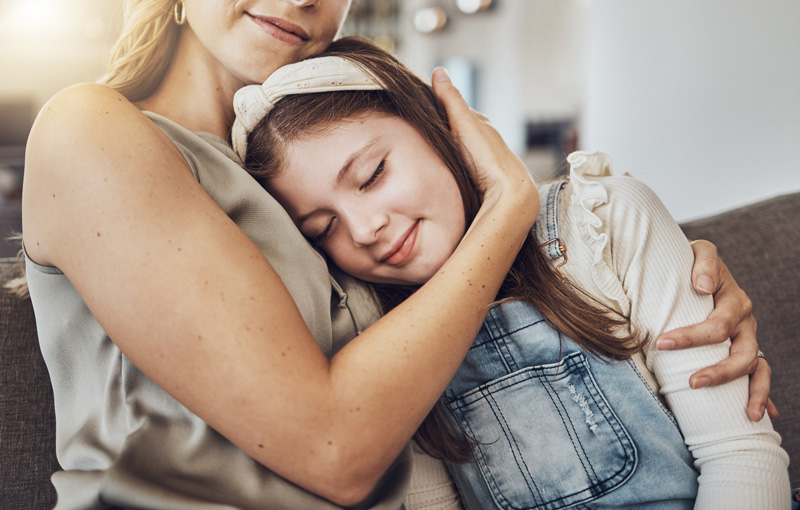 A mom kisses her teenager on the cheek representing establishing a supportive and loving environment for your teen. Get parenting support in Therapy for Teens in Arlington, MA today.