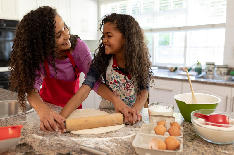 A mom and her teenage daughter make cookies in the kitchen 
