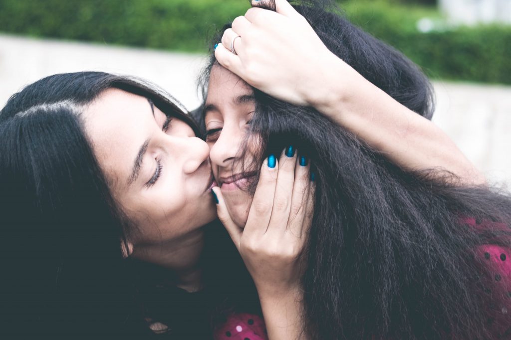 A mom kisses her teenager on the cheek representing establishing a supportive and loving environment for your teen. Get parenting support in Therapy for Teens in Arlington, MA today.