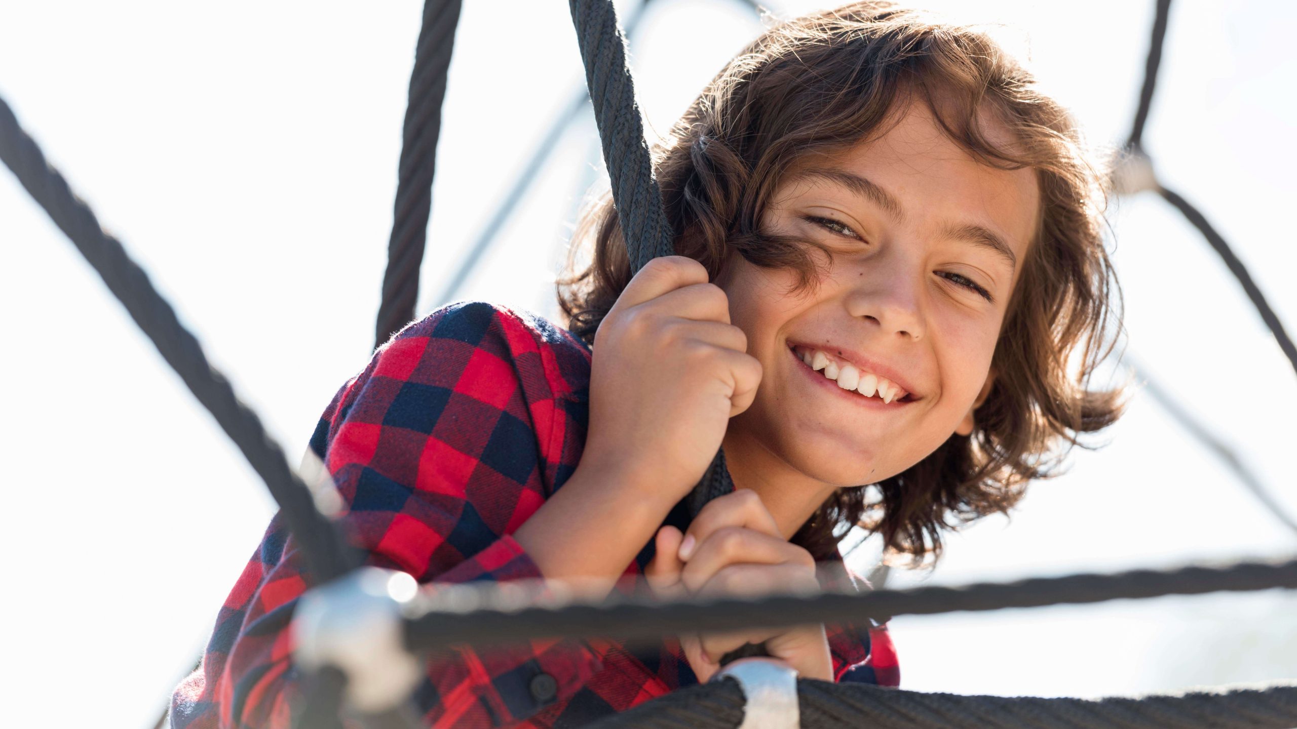 A young boy smiling while playing on a playground. Looking for ways to help your teens with autism in Arlington, MA? See if therapy for teens can help through CBT. Reach out to a teen therapist to see the impact it makes.