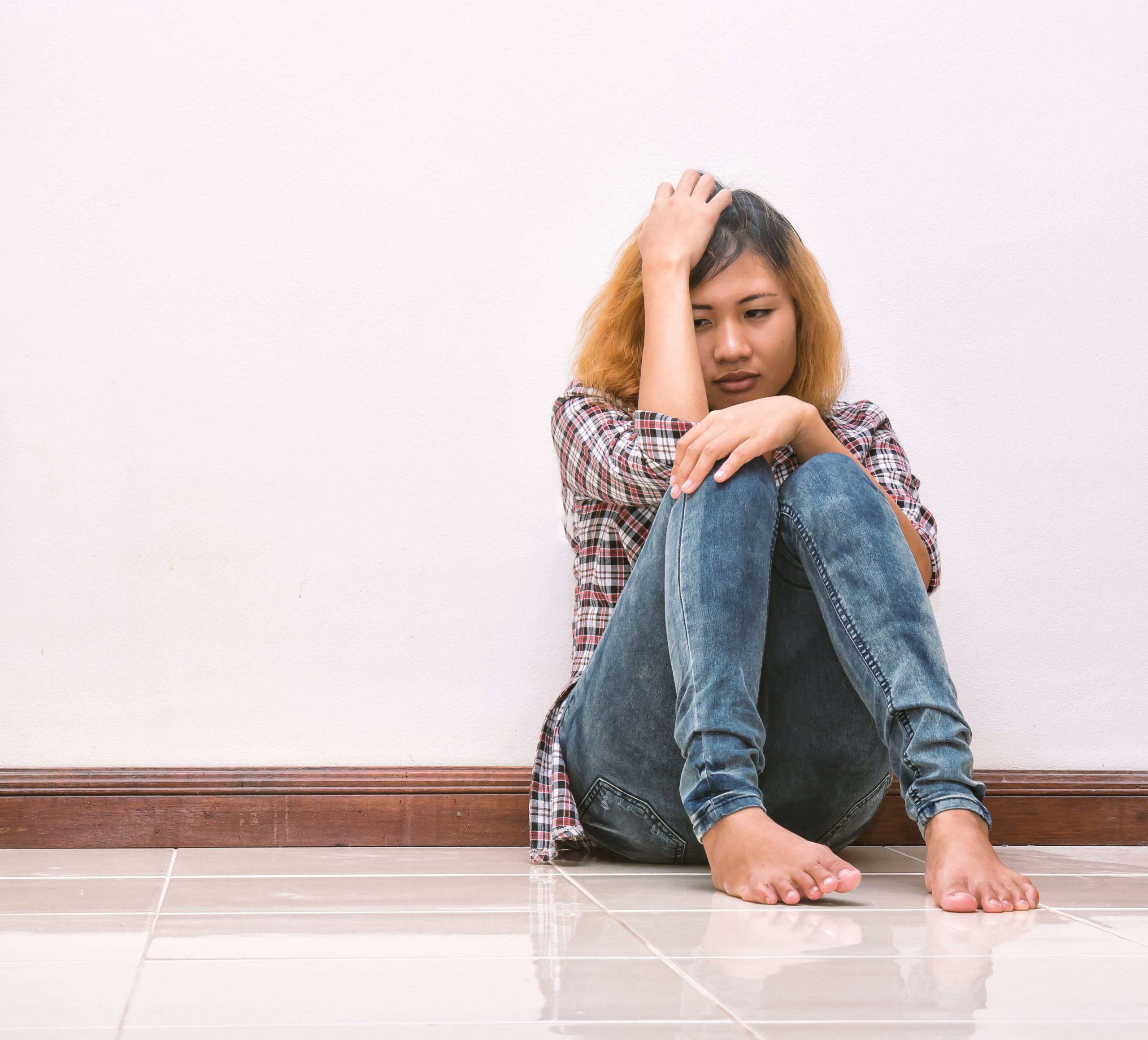 A teen girl sits on the floor. Do you think it might be time for Therapy for Teens in Arlington, MA for your teen? Speak with a teen therapist in MA who can help you!
