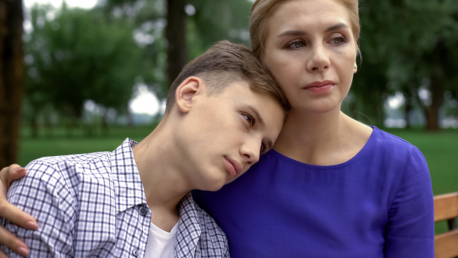 A woman comforts her teen son on a bench in the park. Want to see how therapy for teens in Arlington, MA can help teens with depression? A teen therapist can tell you if it is right for your teen.