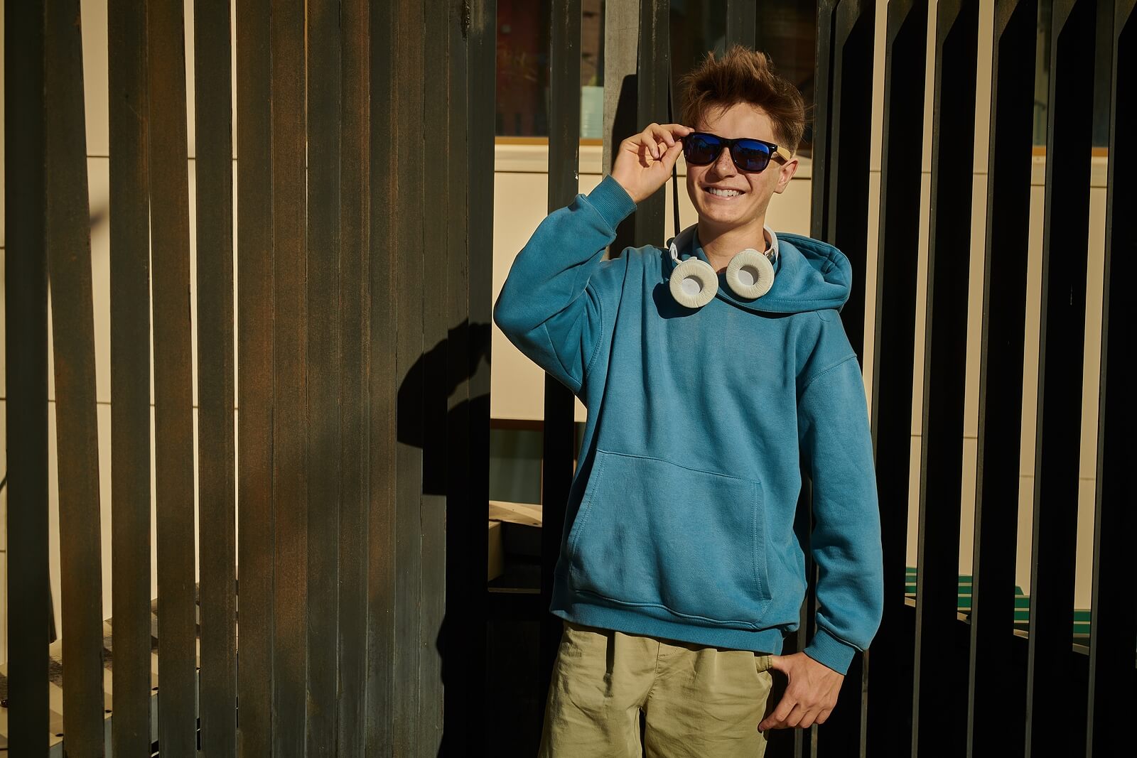 A teen boy walks outside smiling while touching his sunglasses. Help teens with ADHD in Arlington, MA by reaching out to a teen therapist. See how Therapy for teens in Arlington, MA can help your teen!