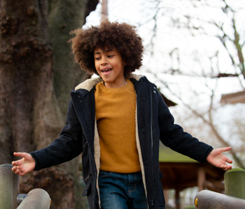 A teen boy walks outside smiling. Help teens with ADHD in Arlington, MA by reaching out to a teen therapist. See how Therapy for teens in Arlington, MA can help your teen!