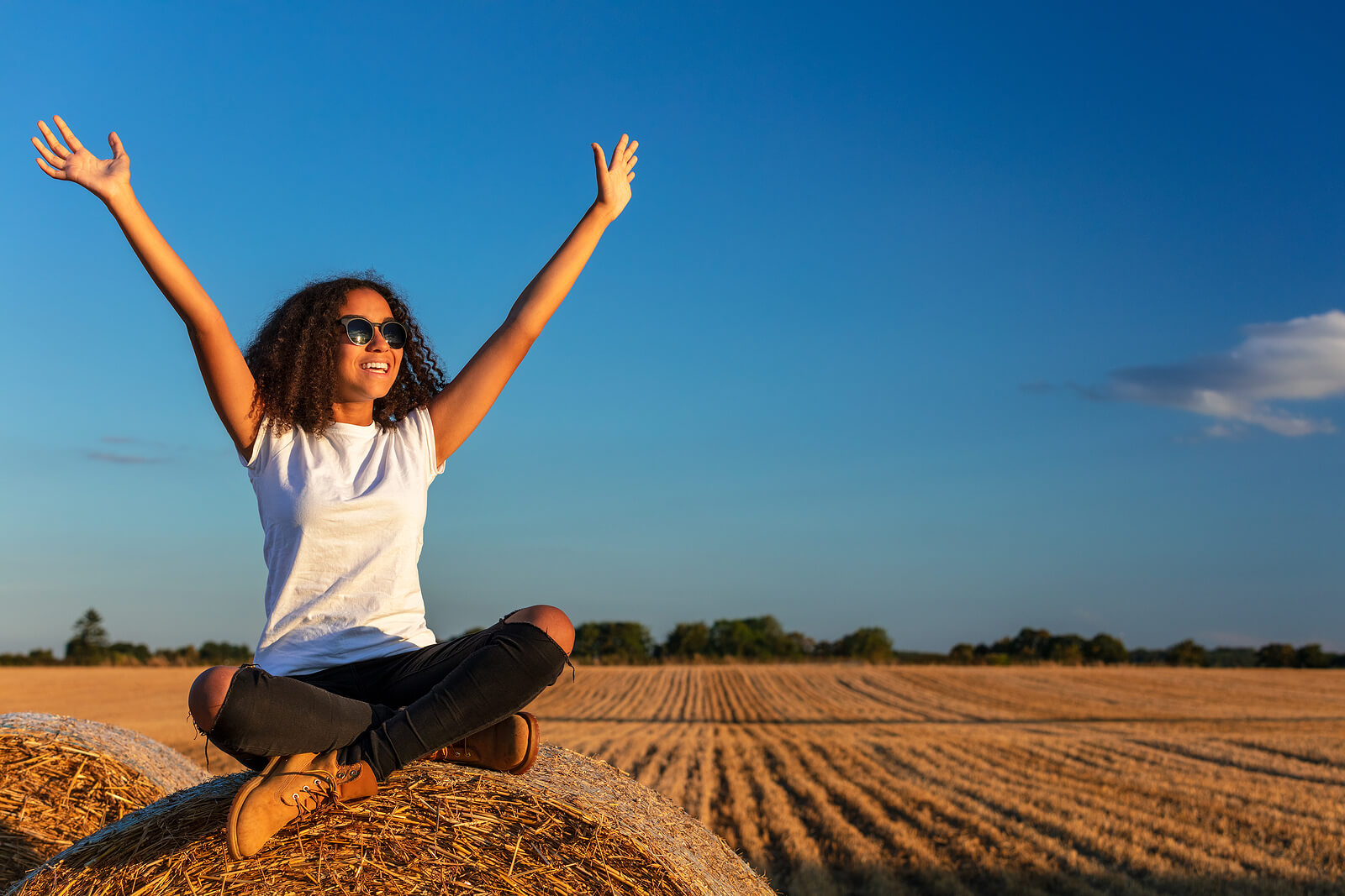 A teen girl sits outside on a pile of hay in a cornfield. Are you wondering how you can help your teen work through their issues as adolescents? Therapy for teens in Arlington, MA can give you those answers. Speak with a teen therapist today to learn more.