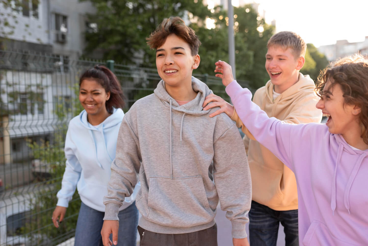 A teen boy stands around smiling with his teen friends in a group. Curious about what Acceptance and Commitment Therapy for Teens in Arlington, MA is? A teen therapist in MA can help answer those questions while helping your teen.