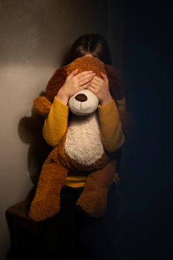 A child sits with a stuffed animal while covering their face. This could represent the isolation that a depression therapist in Arlington, MA can offer support with overcoming. Search for depression therapy in Arlington, MA and how a child psychologist Arlington, MA can help today.
