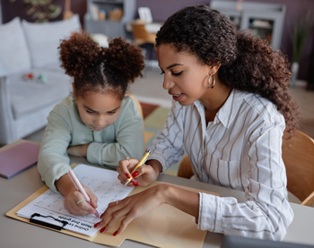 A child smiles while sitting next to a woman with a clipboard taking notes. This could symbolize the support a depression therapist in Arlington, MA can offer for children experiencing depression. Search for depression treatment in Arlington, MA today.