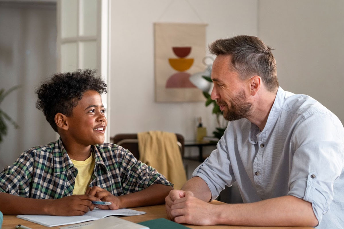a male therapist sits with a young African-american boy during a session