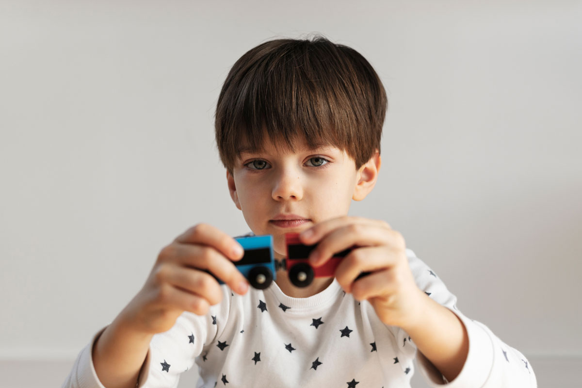 a young boy holds up toy wooden train