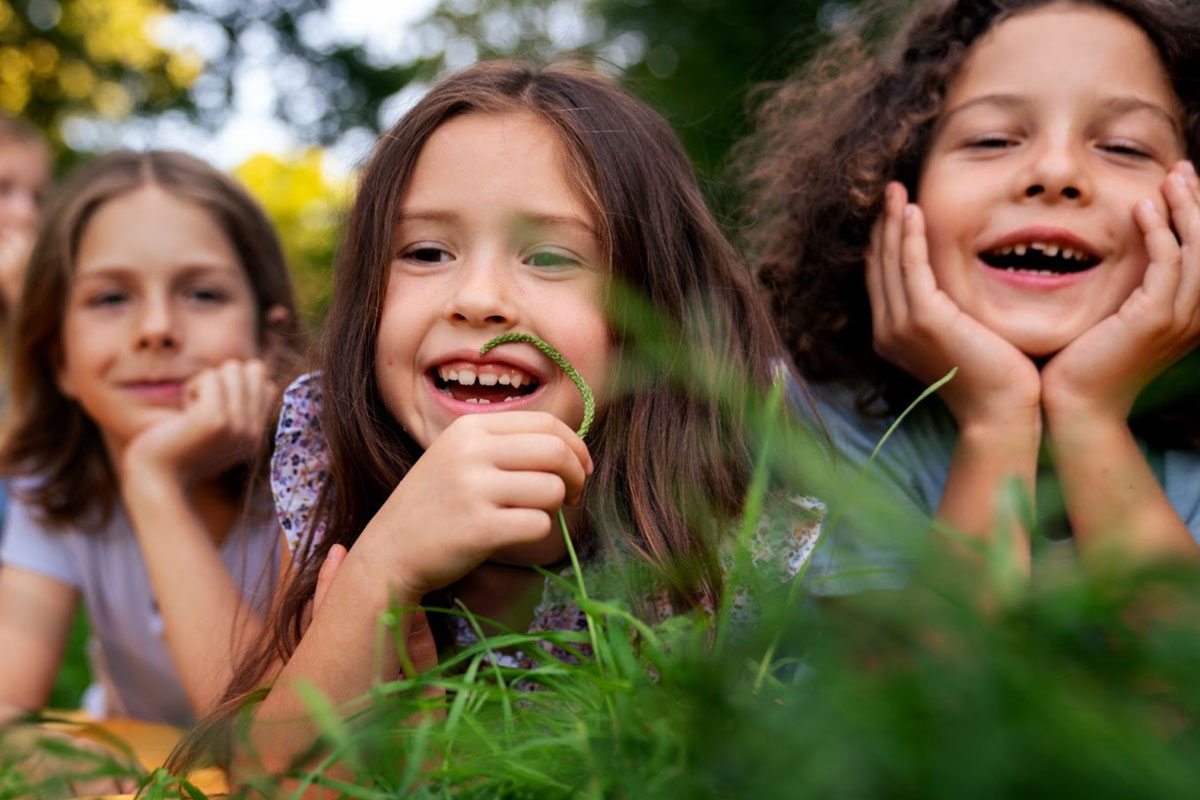 three young girls laid on their stomachs in the grass